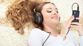 smiling woman lying on carpet and listening to music