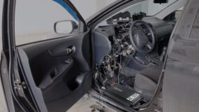 The inside of a grey vehicle with the dash taken apart and wires exposed being worked on